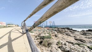 Une promenade en bord de mer, avec une côte rocheuse, un ciel dégagé et un bâtiment en arrière-plan.