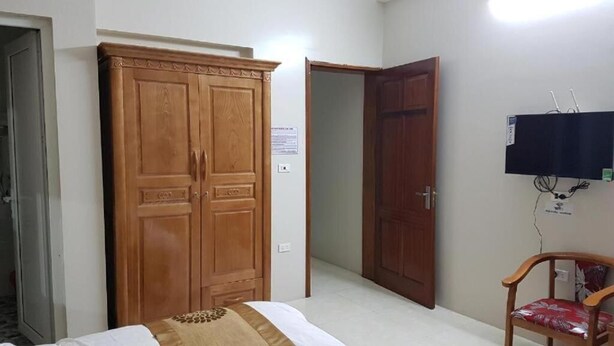 Ein Zimmer mit einem Bett, einem Holzschrank, einer Holztür und einem an der Wand befestigten Fernseher.