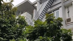 Ein Hotel mit einer Treppe, die zu einer oberen Etage führt, umgeben von üppigem Grün.