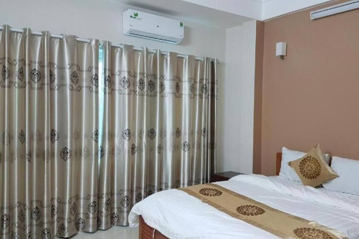 Ein Hotelzimmer mit Bett, Vorhängen, einer Klimaanlage und einer Wandleuchte.