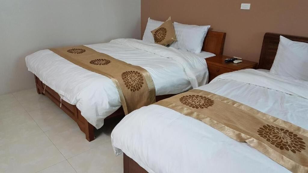A hotel room with two beds, each with white bedding and a decorative beige runner.