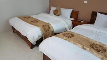A hotel room with two beds, each with white bedding and a decorative beige runner.