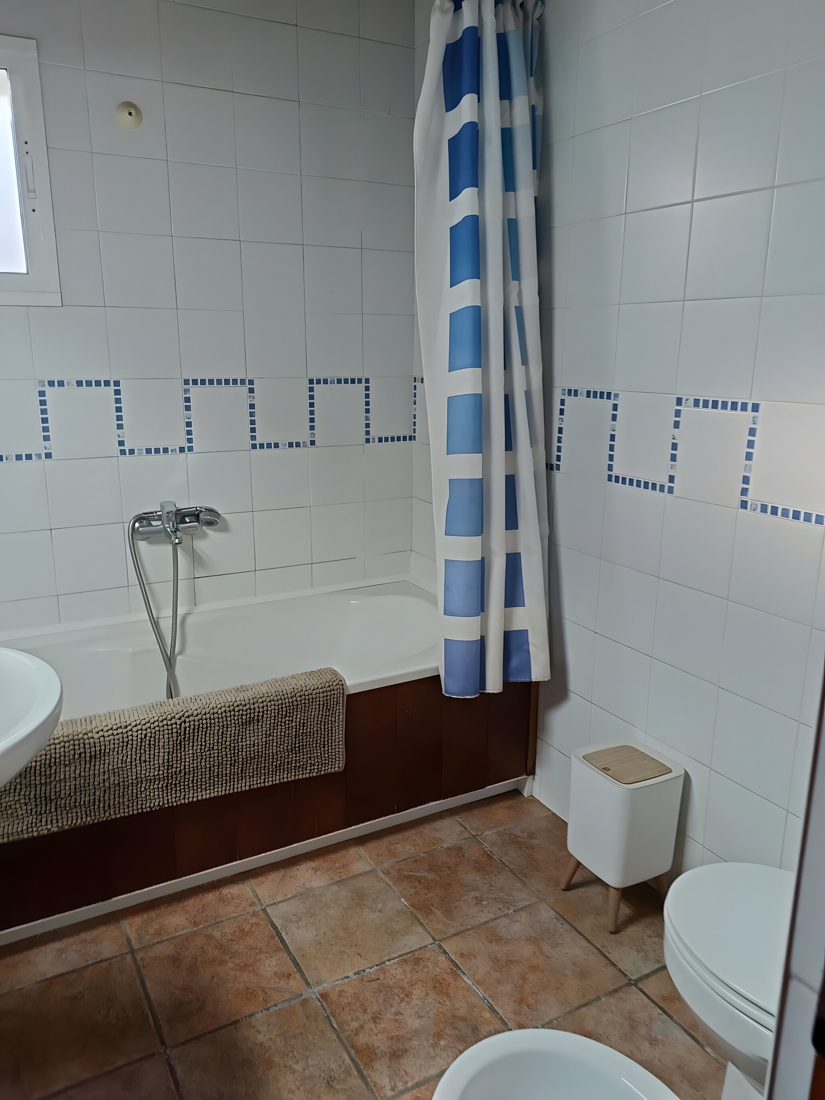 Et badeværelse med badekar, bruseforhæng, toilet og håndvask.