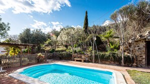 A rectangular swimming pool with a stone wall and a wooden deck surrounding it. - Holiday Home 'Casa Rural Villa Campito' with Mountain View, Private Pool and Wi-Fi (Antequera)