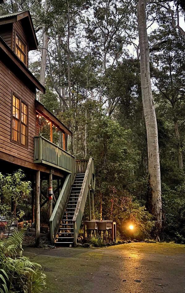 A wooden cabin with a staircase leading to a balcony, surrounded by dense forest. - Tallgums - Immerse Yourself in Ancient Rainforest (Salisbury)