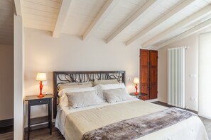 A bedroom with a bed, two bedside tables, a radiator, and a wooden wardrobe.