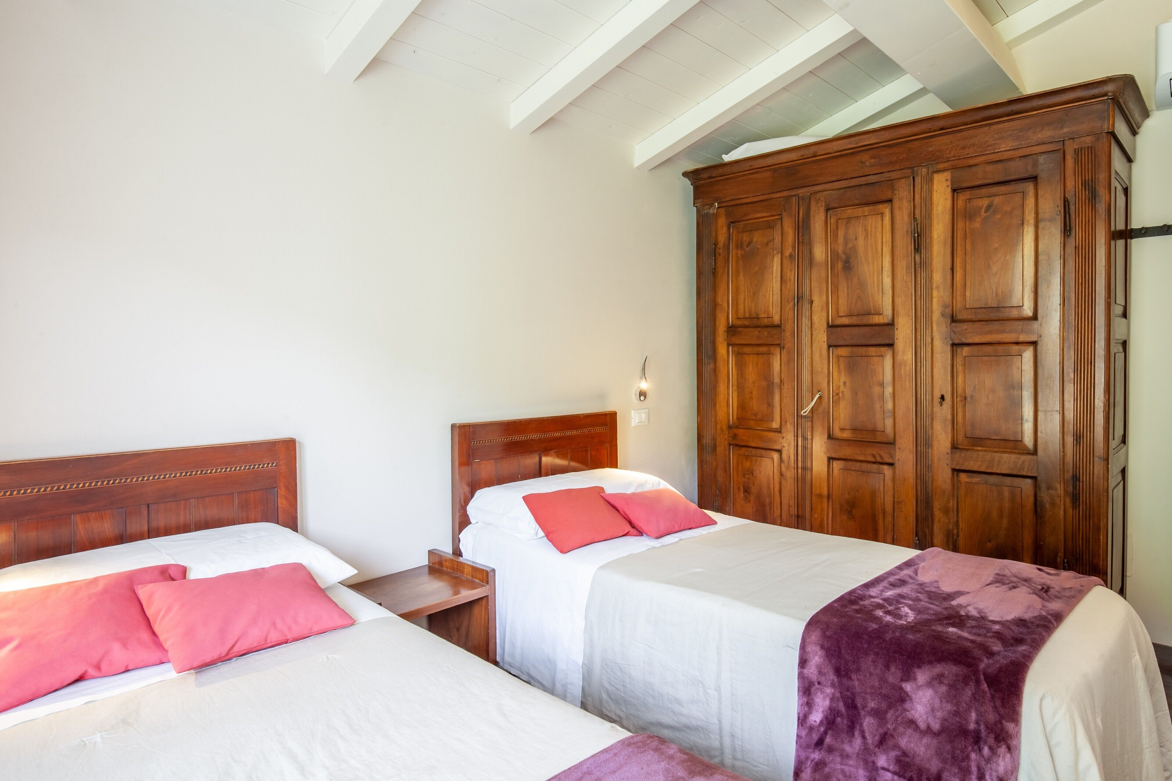 Ein Schlafzimmer mit zwei Betten, einem Holzschrank und einem Nachttisch.