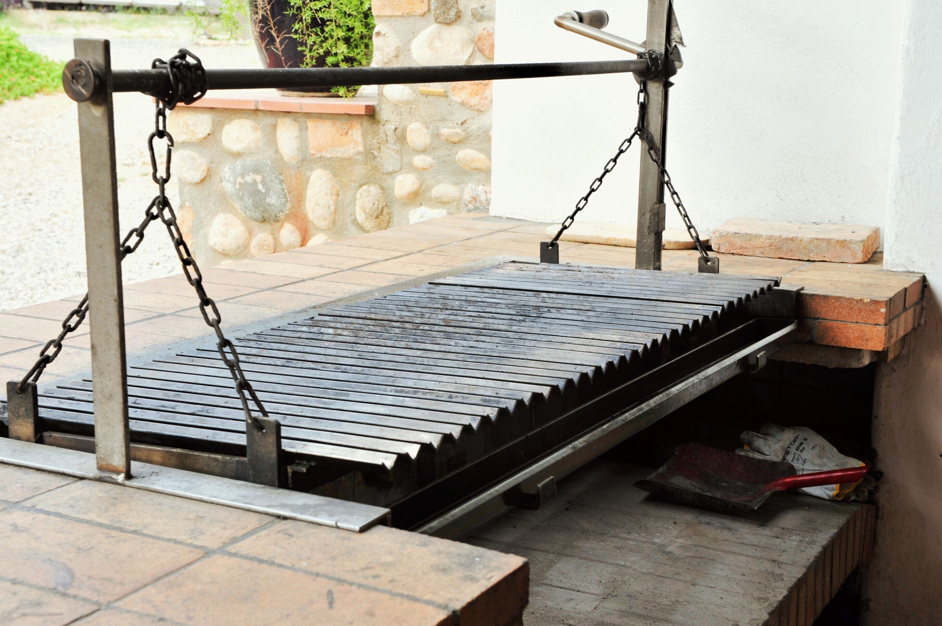 Grelha de metal com correntes, uma parede de pedra e uma estrutura de tijolos.