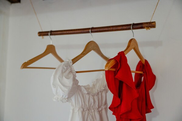 Three wooden hangers with garments on them.