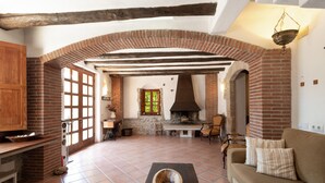 Un intérieur rustique avec des arches en briques apparentes, une cheminée et un coin salon confortable.