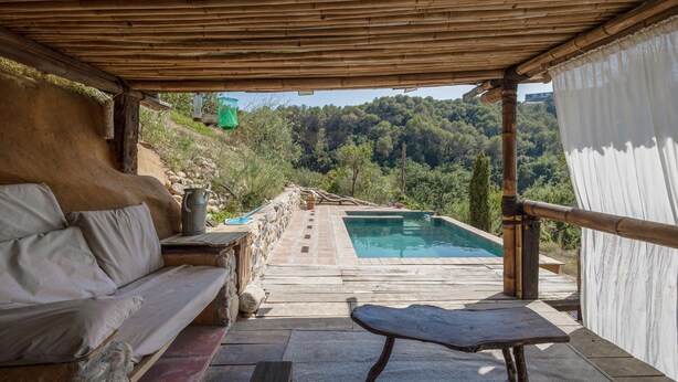 Un espace extérieur abrité comprenant une piscine, un banc en bois et un canapé.