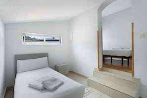 A bedroom with a bed, a nightstand, a window with a view, and a mirror.