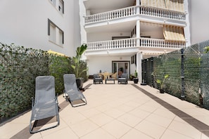 A courtyard with two lounge chairs, a small table, and a sofa.