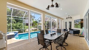 Un patio amplio con piscina, ventanas grandes y mobiliario exterior.