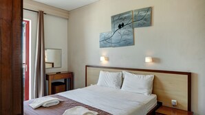 Ett hotellrum med en säng, ett nattduksbord, en spegel och konstverk på väggen.