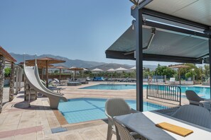 A pool area with lounge chairs, umbrellas, and a slide.