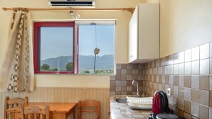 A kitchen with a window, a table, chairs, a sink, and a kettle.