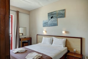 A hotel room with a bed, a nightstand, a mirror, and artwork on the wall.