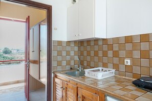 A kitchen with a sink, cabinets, and a balcony door.