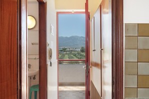A corridor with a view of mountains, a balcony with a railing, and a door leading to a bathroom. - Studio Apartment 'Golden Sun  7' with Sea View, Shared Pool and Wi-Fi (Tigaki 0)