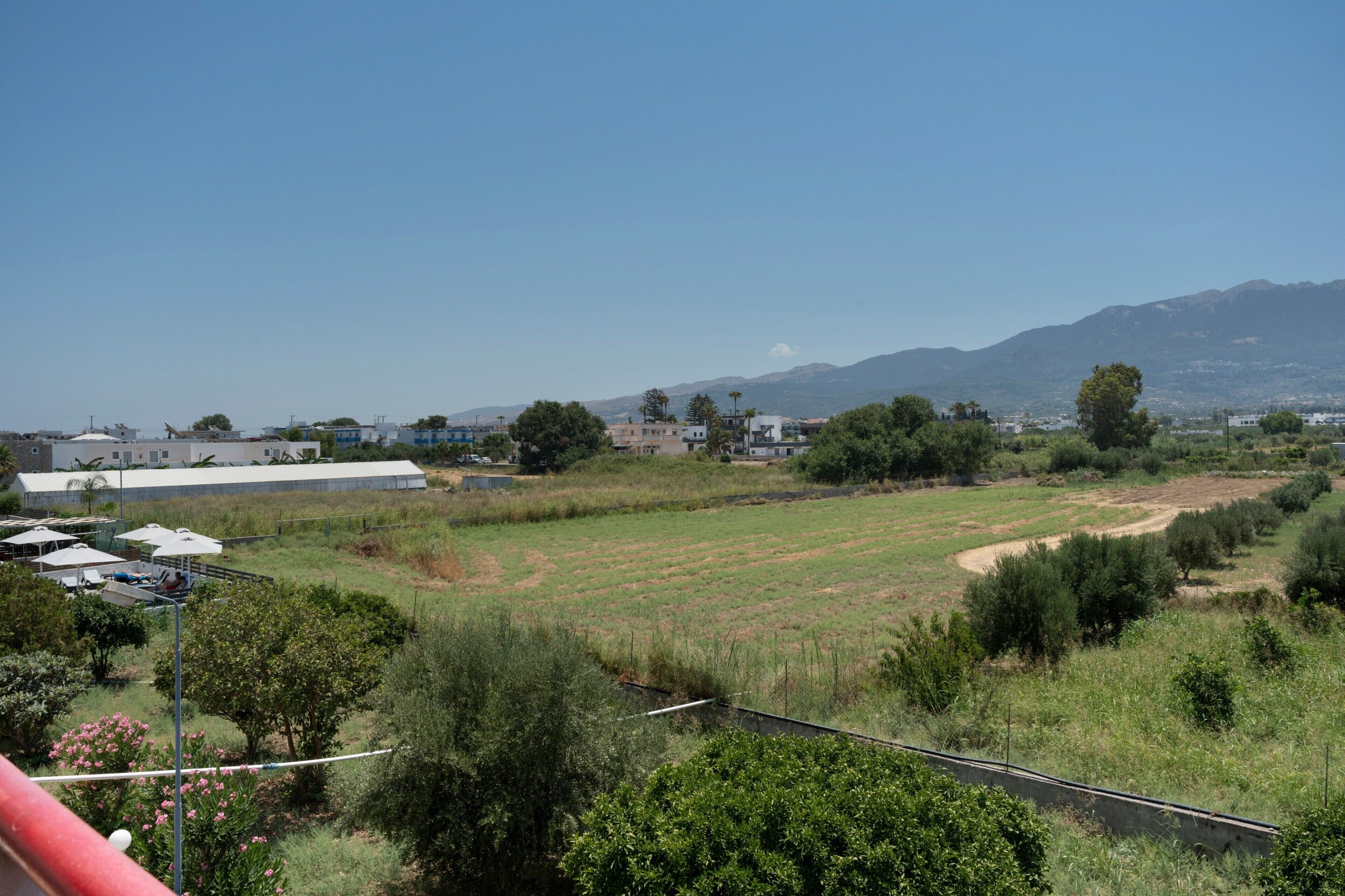 A view of a rural landscape with fields, trees, and distant mountains.
