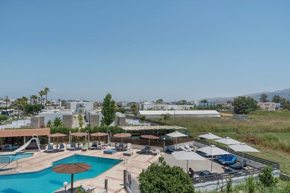 Een resort met een zwembad, ligbedden, parasols en uitzicht op de omgeving.