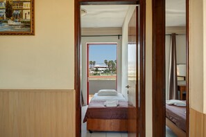 Een kamer met een bed, een deur naar een balkon en een schilderij aan de muur.