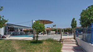 A pool area with lounge chairs, umbrellas, and a building with outdoor seating. - Apartment 'Golden Sun Two-bedroom Apt 4' with Sea View, Shared Pool and Wi-Fi (Tigaki 0)
