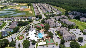 Zona residencial con edificios de apartamentos, piscina, canchas de tenis y una gran masa de agua.