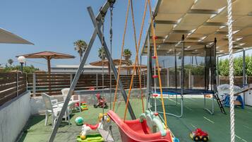 A playground with swings, slides, and a trampoline.