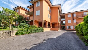 A multi-story residential building with balconies, a driveway, and surrounding greenery. - Apartment 'My Town Home' with Balcony, Wi-Fi and Air Conditioning (Torri del Benaco)