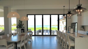 A modern kitchen with a large island, white cabinetry, and pendant lighting. - Coral Cove Villa - New Large 7 Bedroom Modern Luxury Villa + Concierge (George Town)