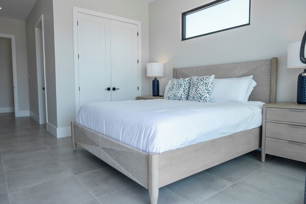 Un dormitorio con cama, mesitas de noche, una lámpara y una puerta.