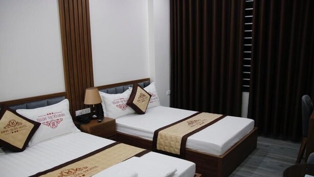 Dos camas individuales con cabeceros de madera y ropa de cama blanca, cada una con una almohada marrón y un corredor beige.