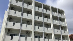 En bygning med flere etager, med altaner og aircondition, og en blå himmel.