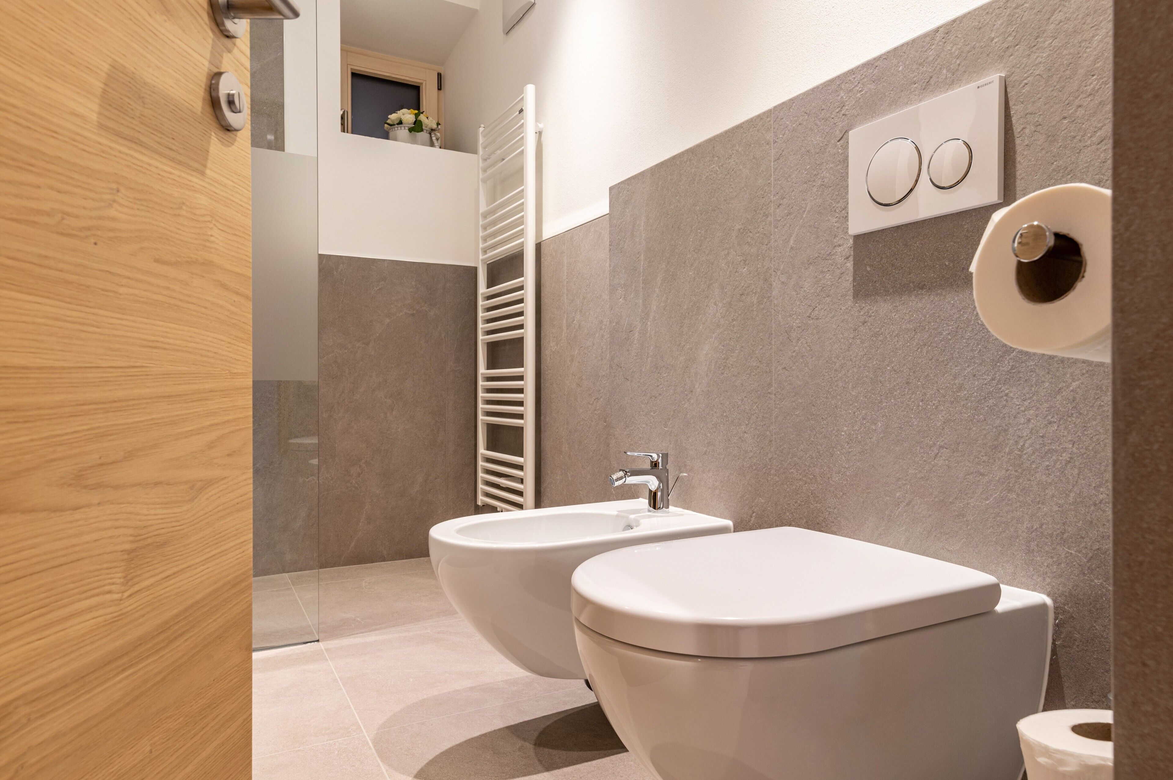 A modern bathroom with a bidet, toilet, and towel rack.