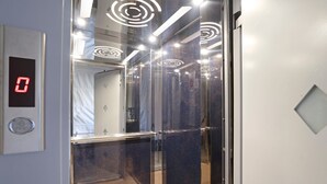Ein Aufzug mit digitaler Anzeige, Glastüren und einem Marmorboden.