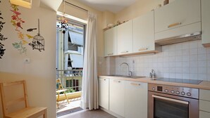 Eine Küche mit weißen Schränken, einem Edelstahlbackofen und einem Fenster mit Vorhang.