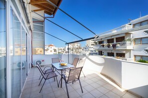 A balcony with a table and chairs, a glass door, and a view of the cityscape.