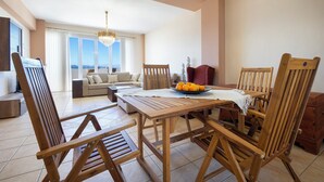 Ein Essbereich mit Holzmöbeln, einem Tisch mit einer Fruchtschale und Blick ins Freie.