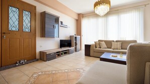 Ein Wohnzimmer mit Sofa, Couchtisch, Fernseher und einer Kristallleuchter.