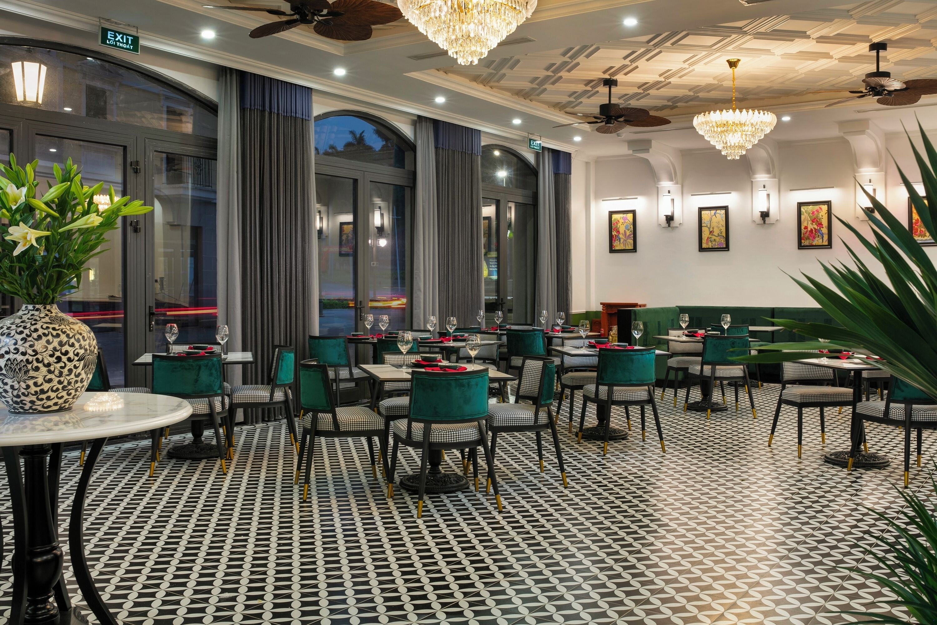 A restaurant with a patterned floor, green upholstered chairs, and a chandelier.