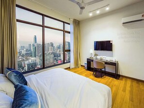 Une chambre d’hôtel dotée d’une grande fenêtre donnant sur la ville, d’un lit avec des oreillers, d’un bureau avec une chaise et d’un appareil de climatisation.