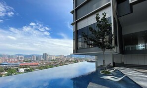 Un hôtel moderne doté d’une piscine à débordement sur le toit, offrant une vue panoramique sur la ville.