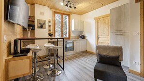 Une cuisine de taille réduite avec un coin bar, un plafond en bois et une grande fenêtre.
