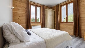 Une chambre à coucher avec un lit, des murs en bois et de grandes fenêtres.