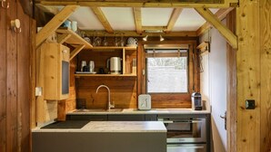 A compact kitchen with wooden walls, a built-in sink, and a window.