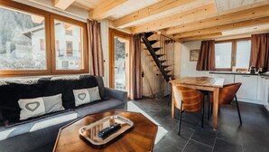 A cozy cabin interior with a sofa, a dining table, and a staircase.