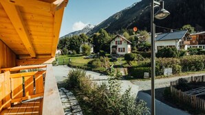 A wooden balcony overlooking a mountain village with houses and a clear sky.