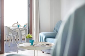 Uma sala de estar moderna com uma mesa redonda, um sofá e um espaço de jantar com cadeiras e uma mesa.